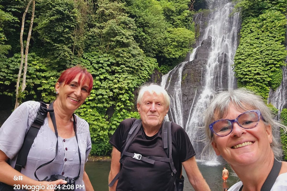 Tiga tamu berpose bersama di bawah air terjun