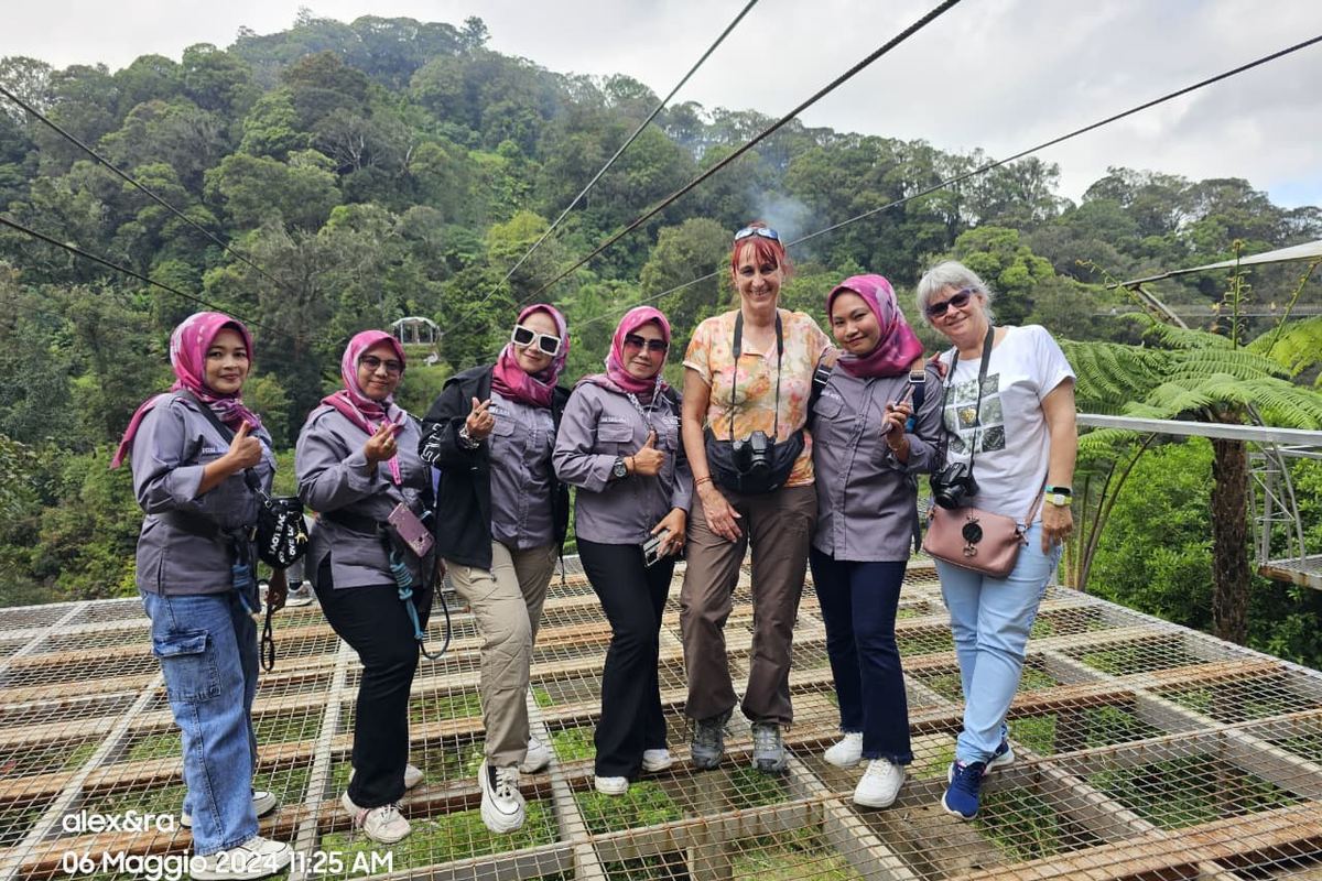 Rombongan tamu berfoto di teras kaca dengan latar perbukitan